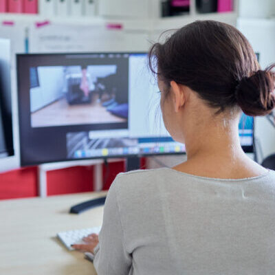 Inhaberin Carmen Schell arbeitet konzentriert am PC. Das Bild zeigt sie von hinten während sie auf den Bildschirm schaut.